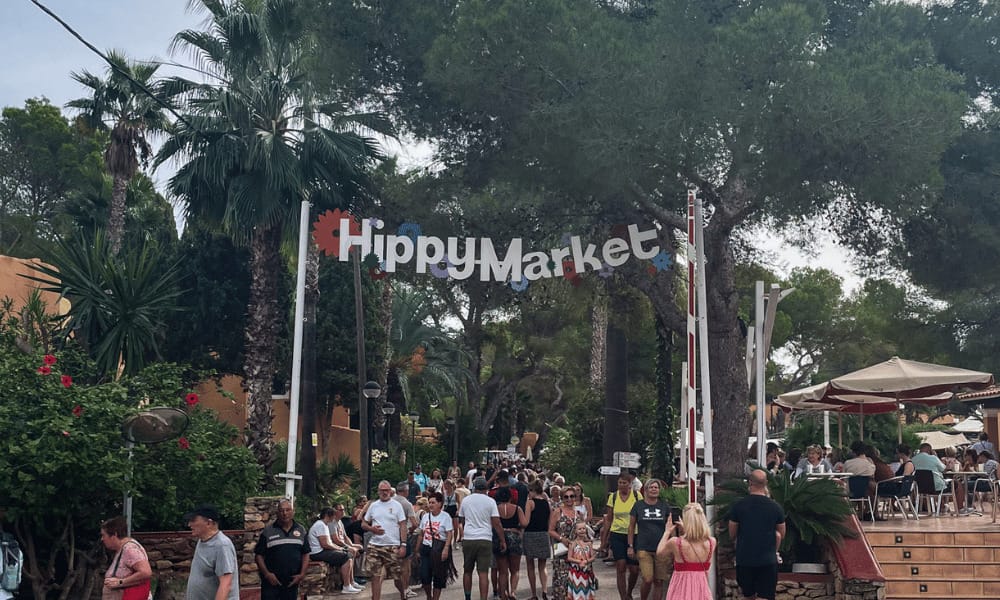 hippy market sign with crowds of people entering and exiting underneath
